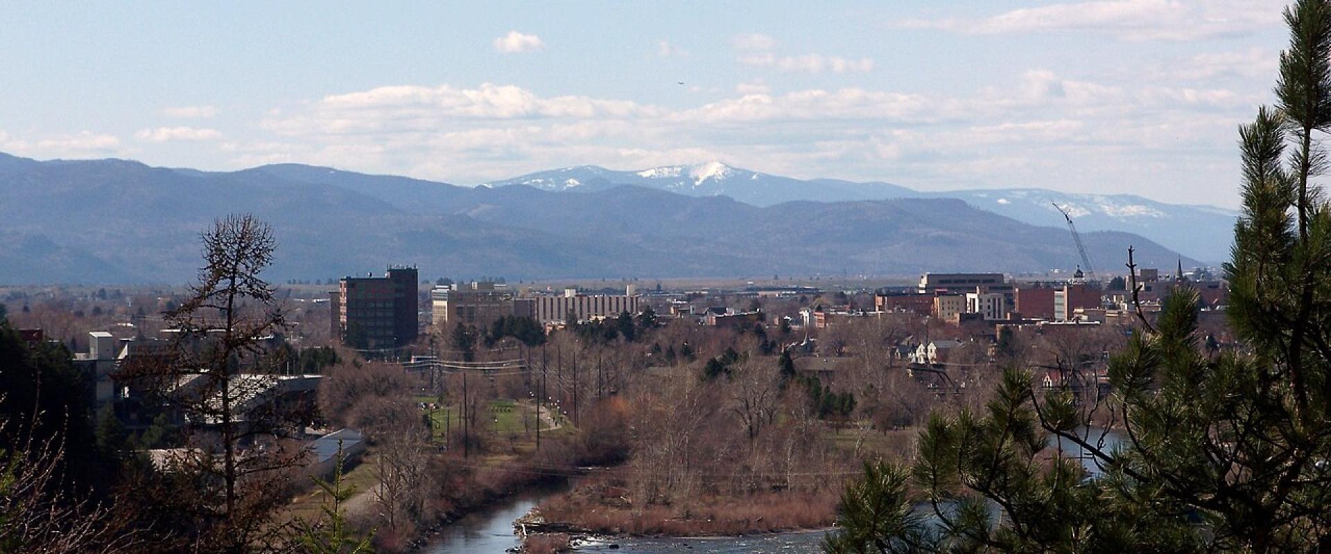 The Clark Fork River flowing through downtown Missoula with mountains behind