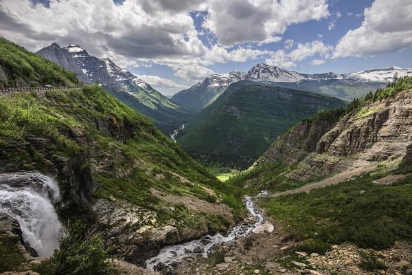 Going-to-the-Sun Road climbing past a waterfall into a green glacial valley in Glacier National Park